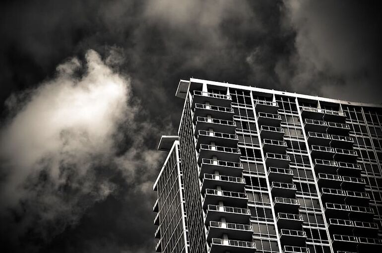 grayscale-photography-of-building-under-cloudy-sky